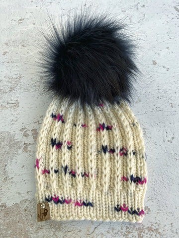 Merino wool in cream with spots of navy and pink.  Topped with a HANDMADE snap on faux fur pom-pom in a very dark navy. Light weight beanie.